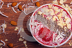 Bowl of fresh acÌ§aiÌ garnished with strawberries and granola on a rustic wood table. AcÌ§aiÌ bowls from above